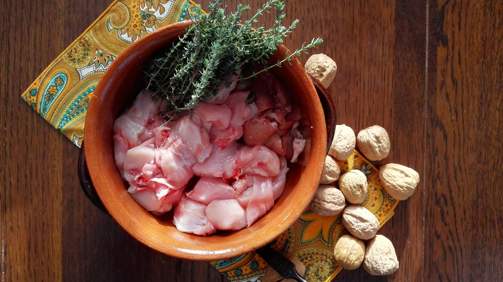 Ingredienti: coniglio e timo in pentola di terracotta e noci sul tavolo