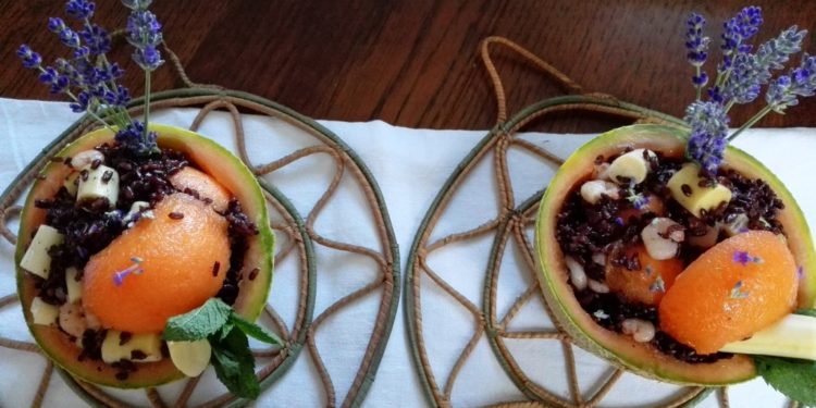 Riso venere nel melone con gamberetti, cuori di palma, pezzi di melone e menta